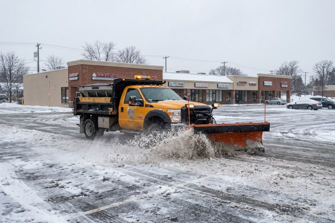 Plow truck pushing snow across a commercial parking lot in Webster, New York