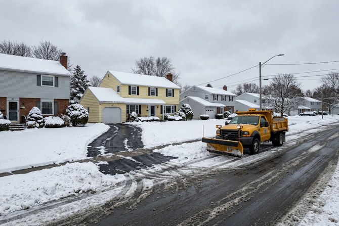Snow-covered residential street in Webster, New York with a cleared driveway